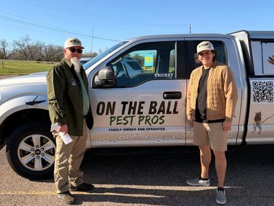 Two men stand beside a pest control truck for On The Ball Pest Pros.