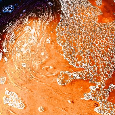 Image of shallow water bubbleing over beach sand 