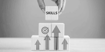 Fingers stacking a pyramid of small wooden blocks displaying upward arrows facing the word, skills. 