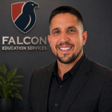 Professional man in black suit smiling before Falcon Education Services logo.