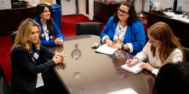 Four women engaged in a meeting around a conference table.