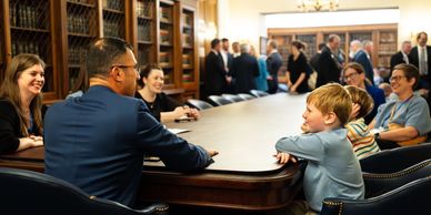 Adults and children engage in a lively discussion around a conference table.