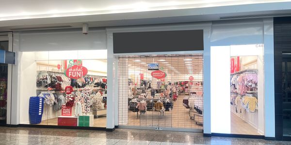 A children’s clothing store with a gated entrance in a mall.