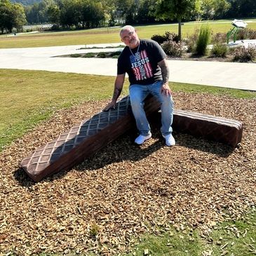 Man sitting on a large chocolate bar sculpture outdoors.