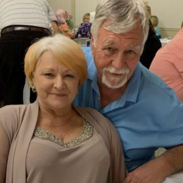 An elderly couple smiling at a social gathering.