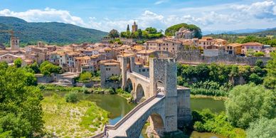 Scenic medieval town with stone bridge and lush greenery.