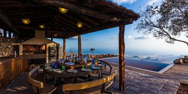 Outdoor dining area with ocean view at sunset.