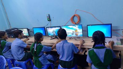 Students in uniforms working on computers in a classroom.
