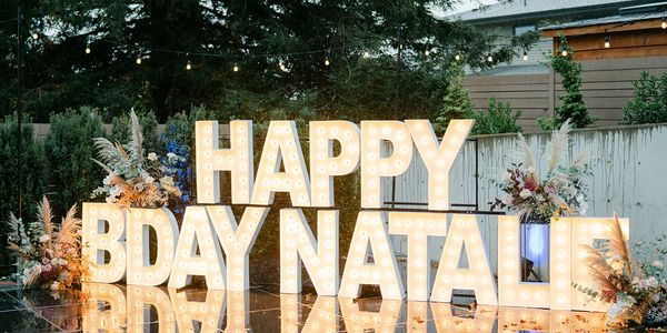 Beautiful birthday sign with floral arrangements in the rain on a backyard patio in Clyde Hill, WA