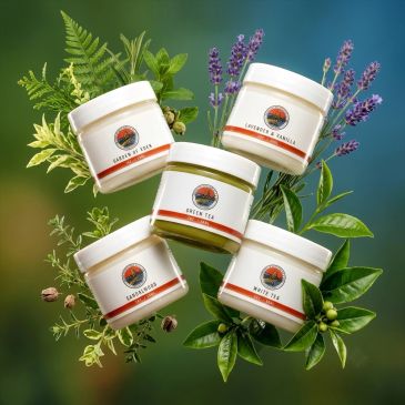 Five tea containers surrounded by fresh herbs and leaves.