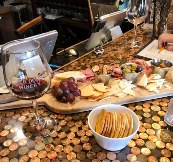 Wine and charcuterie board on a penny-covered table at a winery.