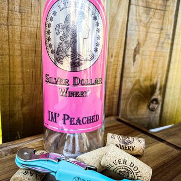 A bottle from Silver Dollar Winery labeled IM' Peached with a corkscrew and corks.