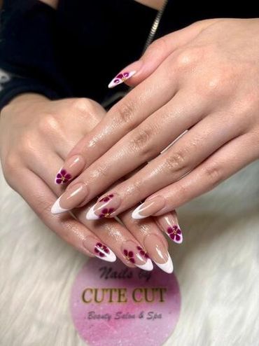 Professional almond-shaped French tip nail art with black floral designs, showcased by Cute Cut Beau