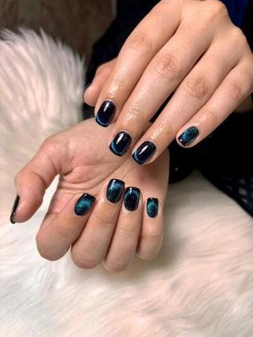 Mesmerizing dark teal and blue magnetic cat-eye gel manicure on short square nails, beautifully done