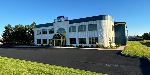 Sunlit commercial building with green lawn and clear blue sky.