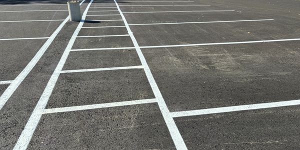A freshly painted parking lot with white lines and concrete barriers.