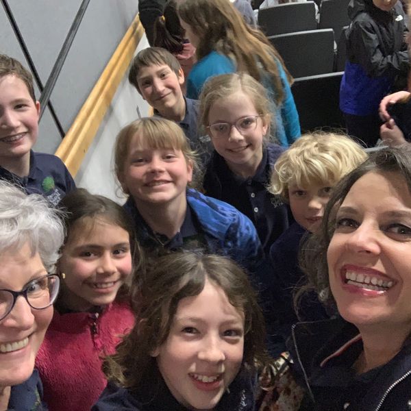 group of smiling FLCS students and teachers at event auditorium