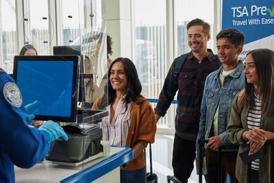 Smiling travelers at TSA PreCheck security screening counter.