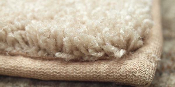 Close-up of beige carpet fibers and edging.