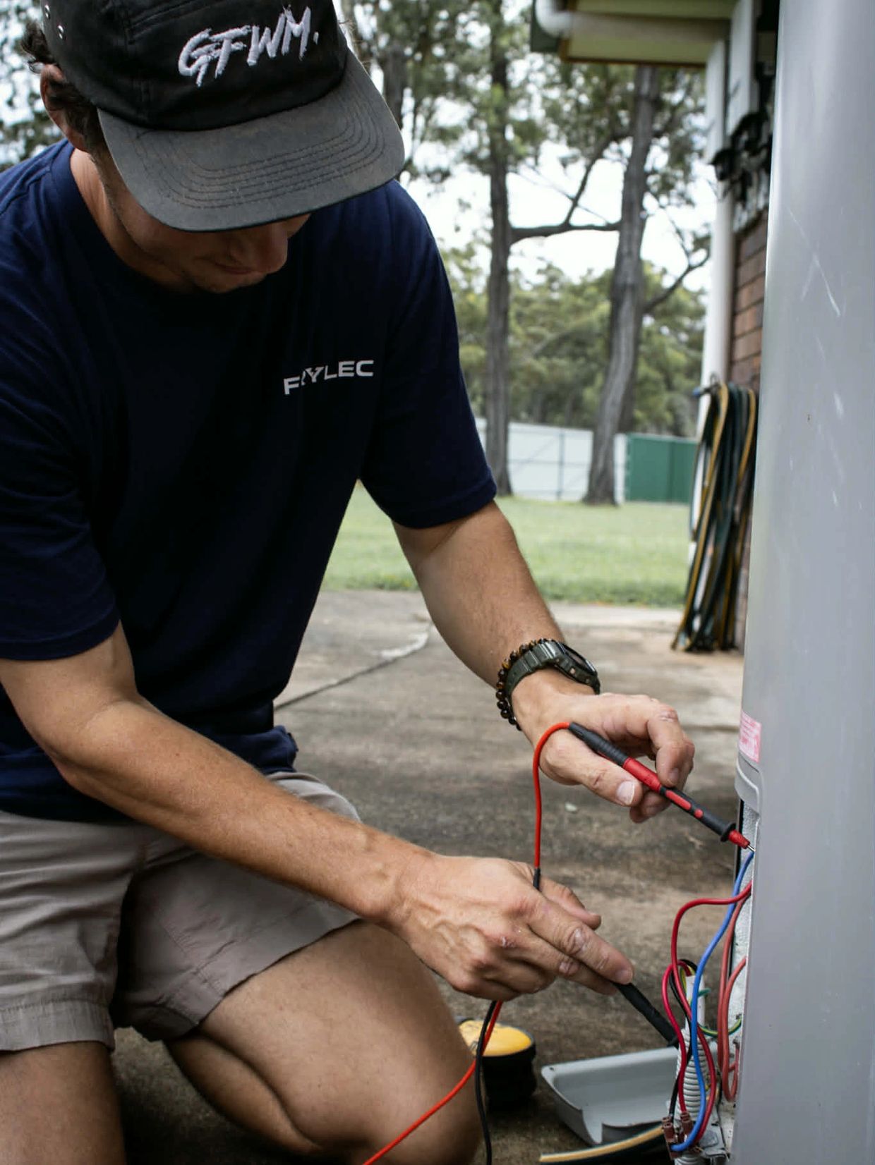 A Photo of a man conducting electrical work on a hot water system