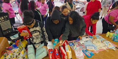 People gathering and selecting items from a table at an event.
