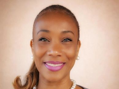 Smiling woman with pearl earrings and necklace.