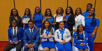 Group photo of people in blue-themed attire holding certificates and trophies.