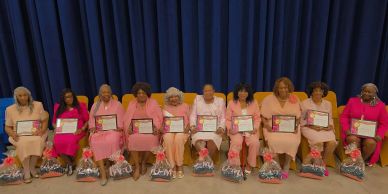Group of women seated holding certificates and gift bags.