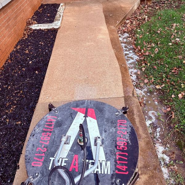 Professional driveway cleaning using high-pressure equipment on residential concrete