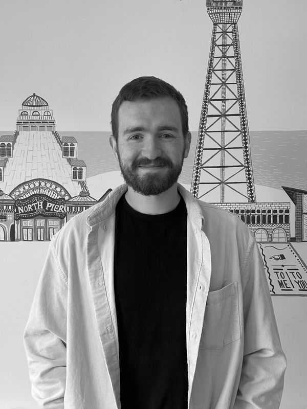 Bearded man smiling in front of a North Pier mural.