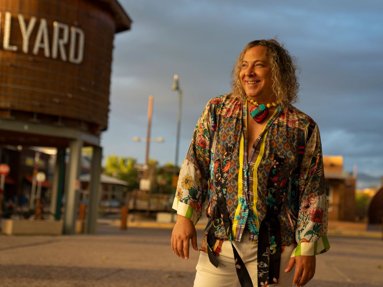 Smiling person in colorful shirt outdoors during golden hour.
