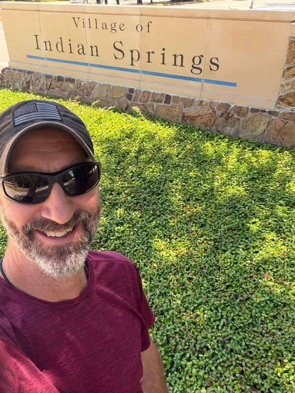 adam taylor the handyman standing in front of the entrance sign for Indian springs, the woodlands, t