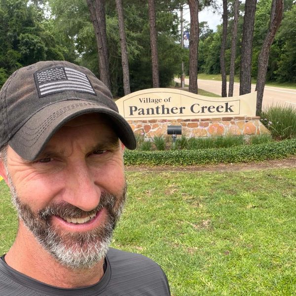 Handyman Adam Taylor in front of the Village of Panther Creek sign in The Woodlands TX