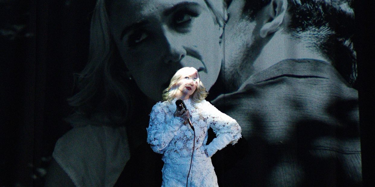 Woman singing with a projected romantic image behind her.