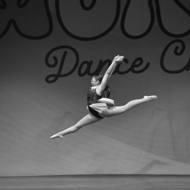 Dancer performing a split leap in midair on stage.