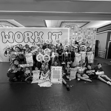 Group of children posing with trophies and awards on stage.