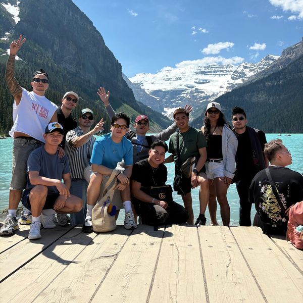 Group of friends posing by a lake with mountains.