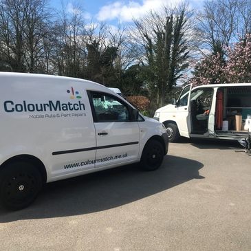 Two white ColourMatch vans parked outdoors under a clear sky.