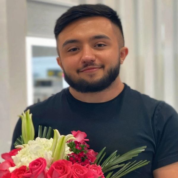 Man with beard holding a bouquet of flowers.