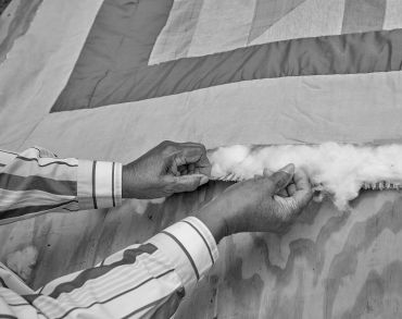 Hands stuffing cotton into a quilt.