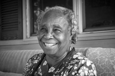Smiling elderly woman in a floral dress.