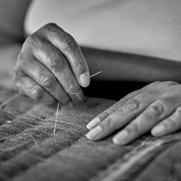 Hands sewing fabric with a needle.