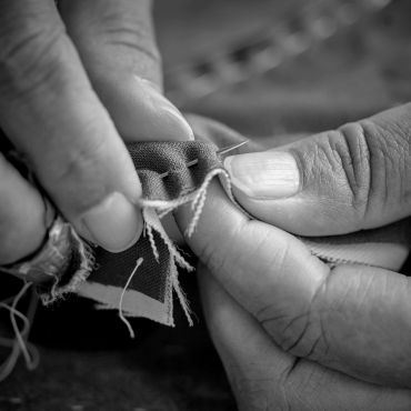 Hands sewing fabric with needle and thread.
