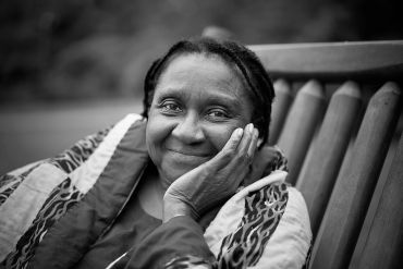 Smiling elderly woman resting her face on her hand.