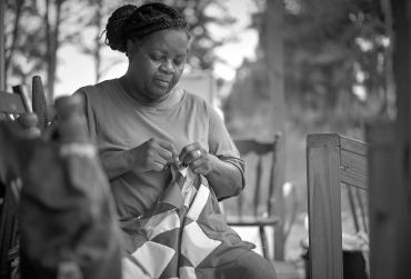 Woman sewing a flag with focus and care.