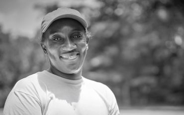 Smiling person wearing a cap outdoors.
