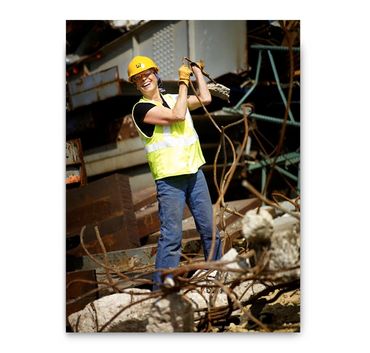 Woman working at a demolition site with safety gear.