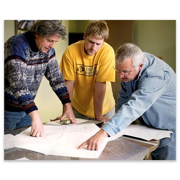 Three men examining blueprints together.