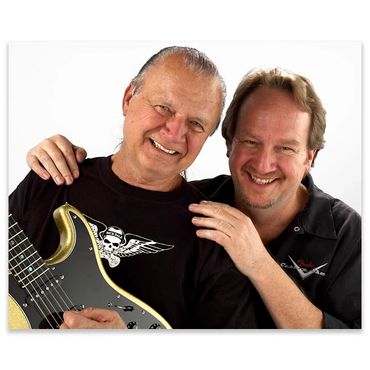 Two men smiling, one holding a guitar.