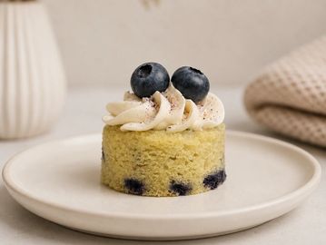Small blueberry cake with frosting and two blueberries on top.